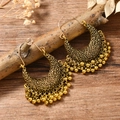 Gros plan de boucles d'oreilles bohèmes dorées en forme de croissant avec pampilles - Or Antique