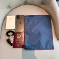 Flat lay of navy nylon organizer bag with daily essentials on a grey textile sofa - Blue