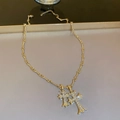 Macro detail of gold plated double cross pendants with sparkling zircon stone settings - Gold Plated Rhinestone Double Cross Necklace