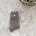 Chaussettes en tricot gris avec texture chinée et bouton blanc sur fond de coton froissé - Taille unique / Gris clair