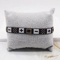 Bracciale di perle Miyuki geometriche oro e nero con motivo a croce su un cuscino grigio - Stile Geometrico Nero Bianco Oro