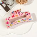 Close-up of pink plastic hair claw clip with colorful heart patterns and LOVE text - 8.5cm Heart Print - Style C Pink Base