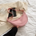 Pink nylon crescent crossbody bag with adjustable strap displayed on aesthetic background - Pink