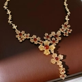 Close-up of vintage flower necklace with champagne and red crystals on brown leather - Necklace-Gold-Brown