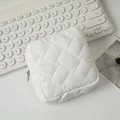Gros plan d'une trousse à maquillage blanche matelassée avec fermeture éclair en argent - Blanc