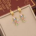 Goldene Hamsa-Hand Ohrringe mit bunten Emaille-Augen auf einem Schmuckständer präsentiert - 3# Ohrringe