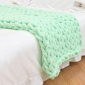 Handmade chunky knit chenille blanket in light green draped over a bed corner - 25*100cm / Aqua Green