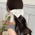 Close-up of a beige polka dot satin bow hair scrunchie tied on a low ponytail hair - White With Black Bow (62# Hair Ring)