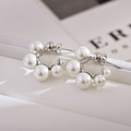 Macro shot of curved pearl earrings with small pearls on a silver metal base - Silver