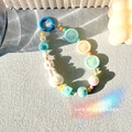 Détail du porte-clés perles colorées avec pompon beige et breloques en relief macaron - Bleu
