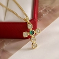 18K vergoldete Kreuzkette mit grünem Edelstein und Zirkonia auf einer Schmuckschatulle - Grüner Edelstein-Stil
