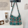 Details einer grün karierten Canvas-Umhängetasche mit Vintage-Knöpfen und Stoffstruktur - Grün