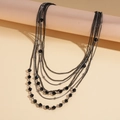Detail view of multi-layered black glass beaded necklace with sleek metallic chains - Black