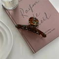Macro detail of amber acetate hair claw with France Handmade gold lettering on a book - Lake Blue Coffee