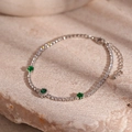 Vista macro di bracciale tennis argentato con pietre di zircone verde su base in pietra - Stile Smeraldo Rotondo / Argento