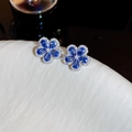 Close-up of elegant flower stud earrings with blue pear-cut stones and crystal pave. - Silver Pin Zircon Flower Earrings