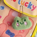 Close-up of green plush frog keychain with pink heart embroidery on a stylish bag - Frog