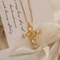 Detailed view of gold cross necklace with heart-shaped crystals and Virgin Mary relief - White