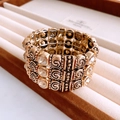 Close-up of vintage gold elastic bracelet with spiral texture and sparkling crystals - Gold