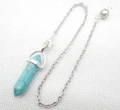 Detail of turquoise hexagonal prism pendant with silver metallic bail on white fabric - Turquoise