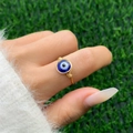 Macro shot of handmade wire-wrapped ring featuring a blue opal evil eye bead - Style 1 Gold+Royal Blue (0581)