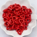 Close-up of red heart-shaped ink-wash ceramic beads piled in a white petal bowl - Red