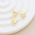 Macro detail of gold plated cubic zirconia alphabet pendants W and S on a ceramic tray - Letter W