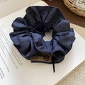 Detail eines dunkelblauen Denim-Haargummis mit Bärenetikett auf einem alten Buch - Denim/Elastik / Haargummi-Blau