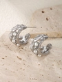 Detalle de pendientes huecos plateados con textura de lava y perlas blancas sobre piedra - Color Acero
