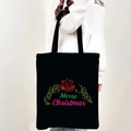 Black canvas tote bag featuring Merry Christmas bells print held by a model in white hoodie - Style 09-Bells Merry Christmas