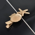 Detailed close-up of golden starfish and seashell hair clip with sleek metal texture - Shell Starfish Duckbill Clip / Gold