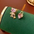 Macro shot of asymmetrical gold bear and heart earrings with pink zircon on green velvet - Gold (Silver Pin/Pink Zirconia)