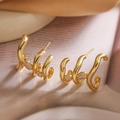 Boucles d'oreilles vagues plaquées or avec zircons cubiques posées sur un tissu soyeux - Spirale Géométrique Irrégulière Dorée