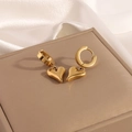 Detail view of heart drop earrings in polished gold on a luxury jewelry box - Gold Heart Dangle Earrings