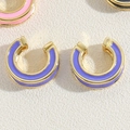 Golden C-shaped hoop earring with purple enamel finish on white textured surface - Purple
