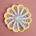 Handmade crochet flower coaster in vibrant pink, purple and yellow gradient yarn - No. 7 Gradient