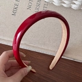Glossy burgundy PU leather headband with anti-slip lining shown on a wooden background - Red