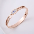 Detalle de brazalete en oro rosa con borde de engranaje y motivo de ojo de la suerte - Oro rosa