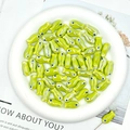 Macro detail of glossy green fish-shaped ceramic beads for DIY jewelry making and crafts - Yellow Green