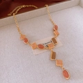 Détail d'un collier vintage doré avec pendentifs géométriques en résine orange - Collier - Or