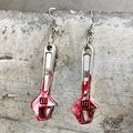 Detail of bloody wrench earring with red splatter design on gray industrial background - Wrench