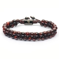 Detail of red tiger eye beads on double-layer braided bracelet with a black metal logo charm - Red Tiger Eye
