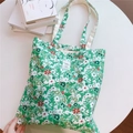 Détail d'un sac cabas en coton à fleurs vertes avec anses renforcées et étiquette tissu - Fond Vert Foncé Fleuri