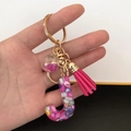 Macro detail of resin letter J keychain with pink sequins, colorful stones and tassel - Small Ball Tassel Clasp / Letter J