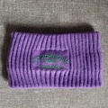 Detail eines lila gerippten Strickstirnbands mit grüner Stockholm-Stickerei in Kontrast - Lila