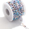 Detailed close-up of colorful faceted crystal beads on a stainless steel chain on a spool - Steel-Blue Multi