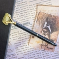 Détail d'un stylo noir avec griffe dorée tenant une pierre de cristal jaune naturelle - Citrine