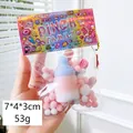 Squishy milk bottle toy in gradient blue and pink with fuzzy pom poms, 53g weight - Hairball Baby Bottle