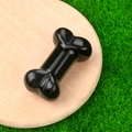 Polished black crystal bone carving miniature displayed on a natural wood tray over grass - Obsidian