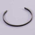 Macro detail of matte black stainless steel open cuff bracelet with brushed metal texture - Black